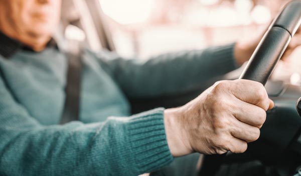 Ein Senior sitzt am Steuer eines Autos.
