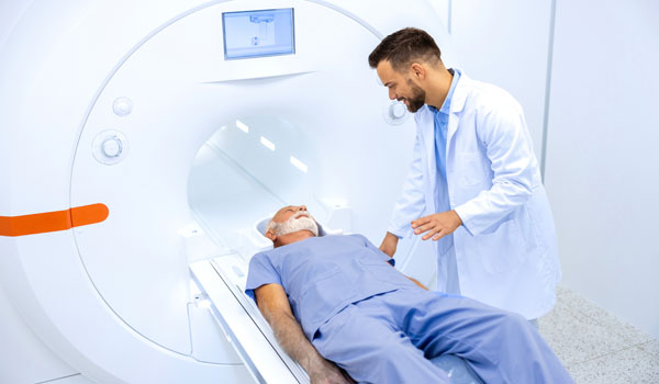 Ein Senior beim MRT, während der Arzt neben ihm sitzt.