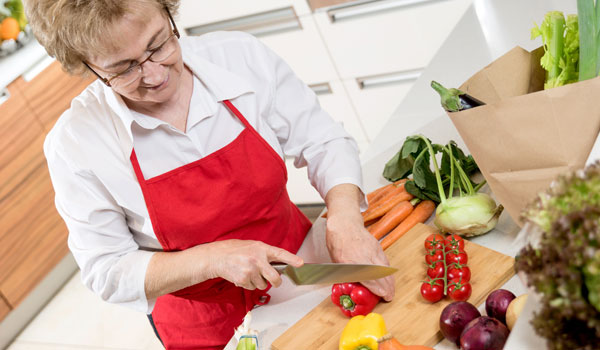 Eine Senioren schneidet in der Küche Gemüse für ihr Intervallfasten.