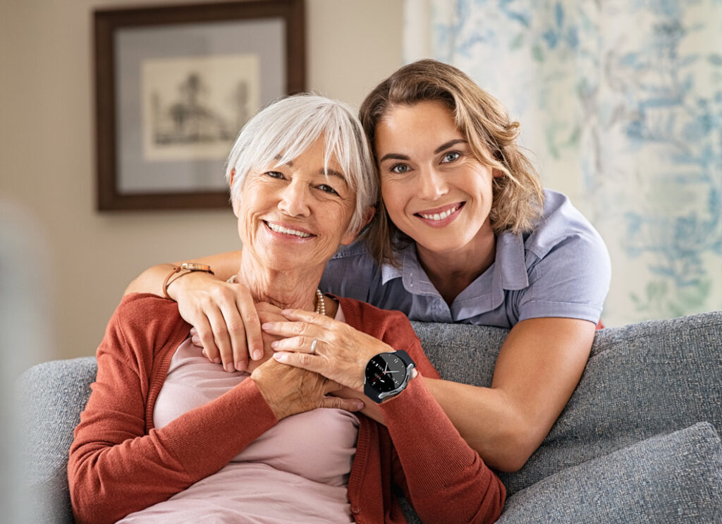 Eine jüngere und ältere Frau. Die ältere Frau trägt ein Notrufgerät.
