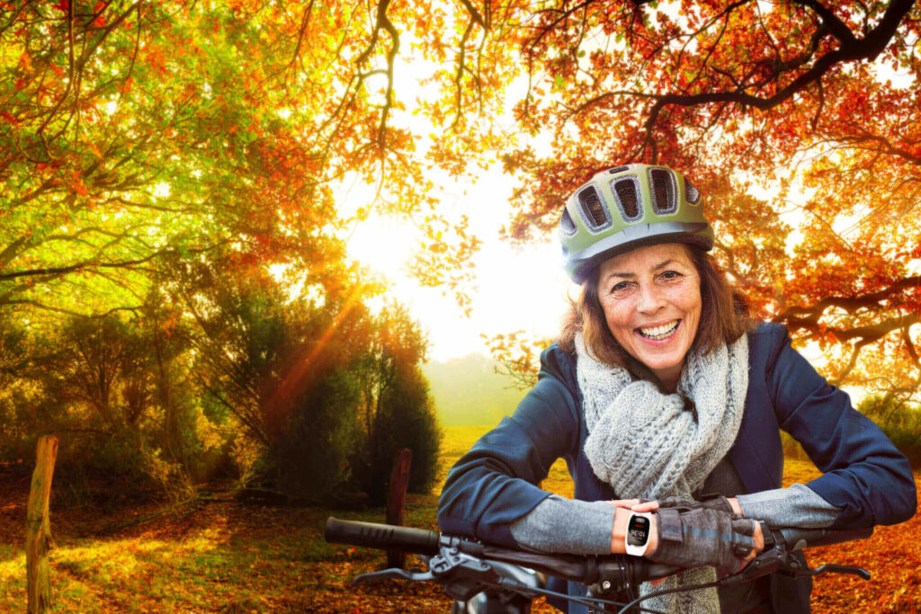 Seniorin im Herbst mit dem Rad unterwegs im Wald.