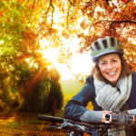 Seniorin im Herbst mit dem Rad unterwegs im Wald.